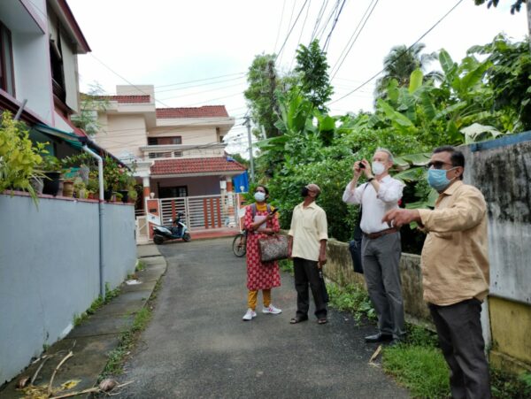 four person look at abuilding in a kochi neigborhood and take photos.