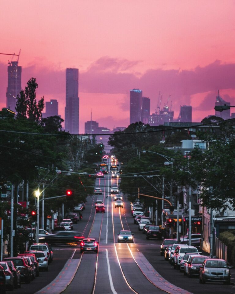 a street in a big city at sunset with skyscrapers in the back.